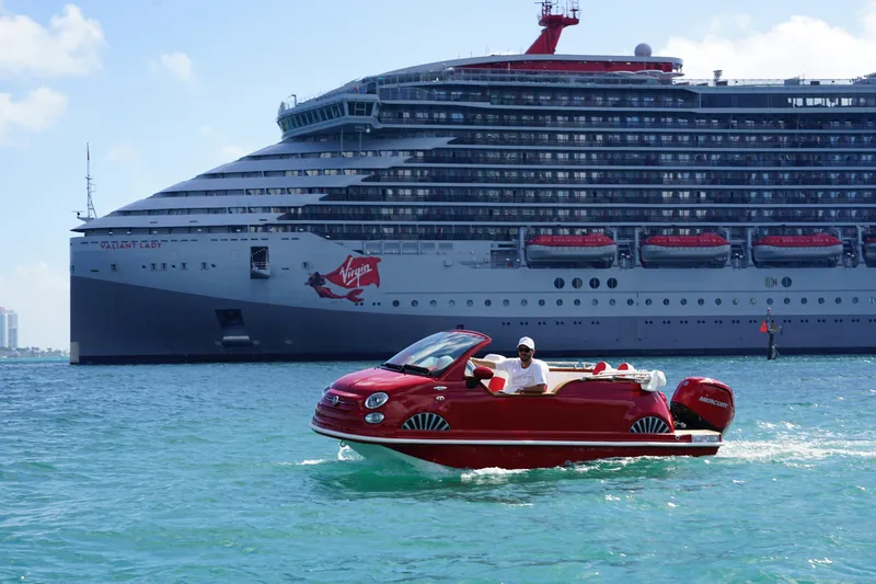 Slide: The Image of Red Fiat 500 Classic boat on water, cruise ship in background, 2025 model. - 4