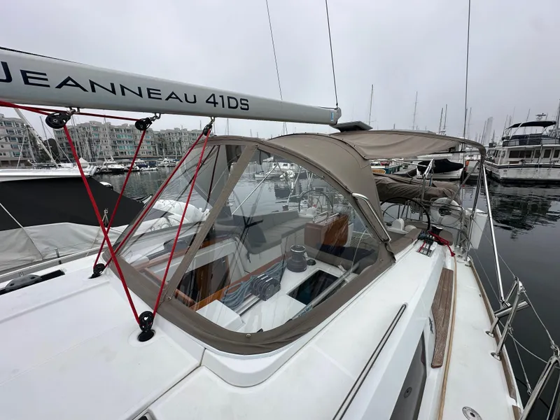Slide: The Image of 2015 Jeanneau 41DS sailboat docked in marina, featuring sleek design and protective canopy. - 25