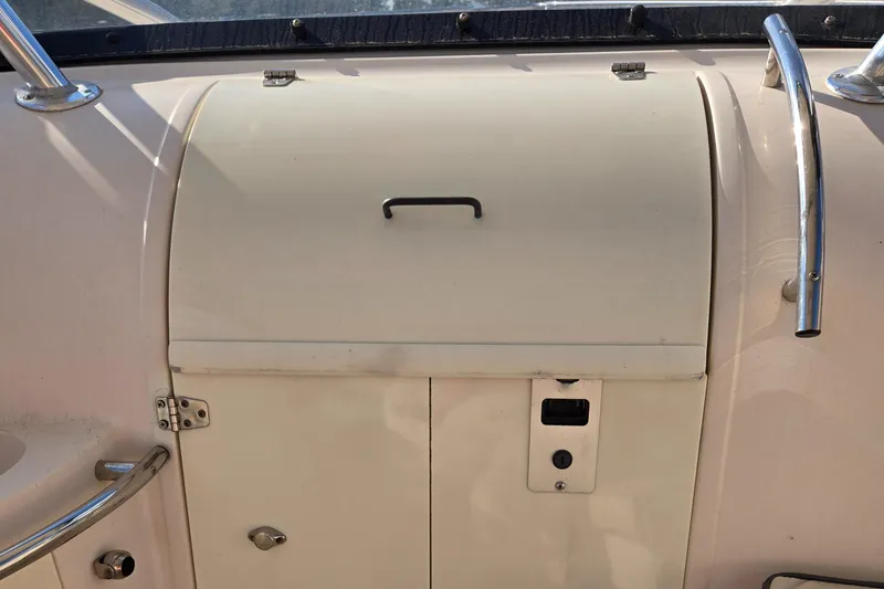 Slide: The Image of Cobia 316 Sport Cabin 2008 boat storage compartment with handle and metal railings. - 23