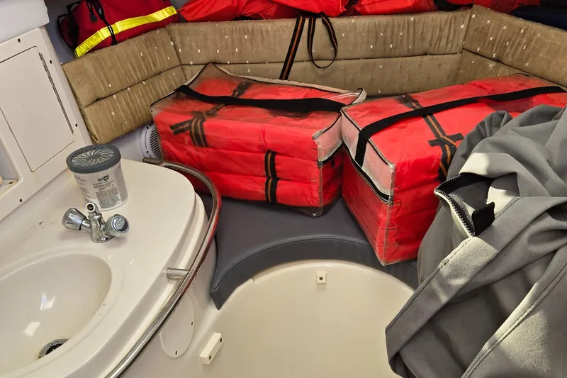 Slide: The Image of 2008 Cobia 316 Sport Cabin interior with red life jackets and compact sink. - 28