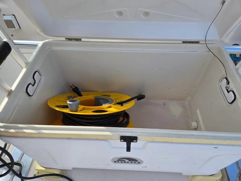 Slide: The Image of Open storage compartment on 2008 Cobia 316 Sport Cabin boat with yellow cable reel inside. - 38