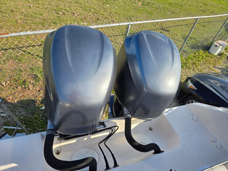 Slide: The Image of Twin outboard motors on a 2008 Cobia 316 Sport Cabin boat, parked near a fence. - 50