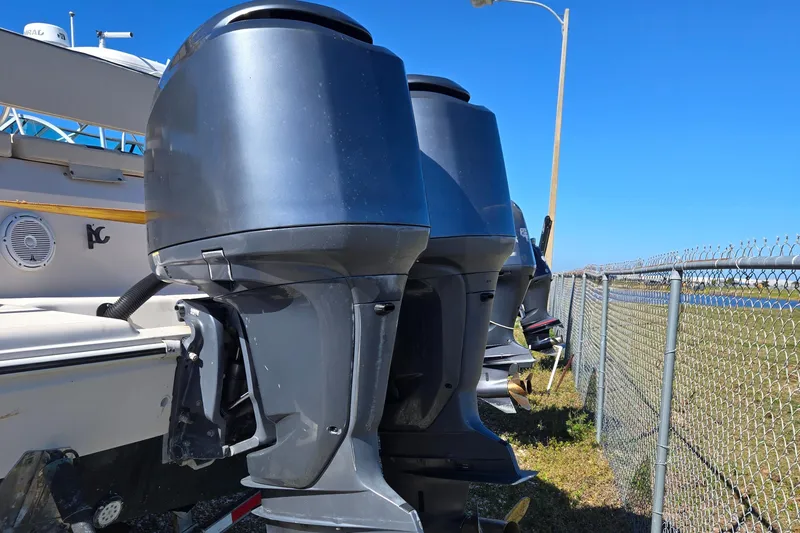 Slide: The Image of 2008 Cobia 316 Sport Cabin with dual outboard motors, parked near a chain-link fence. - 51