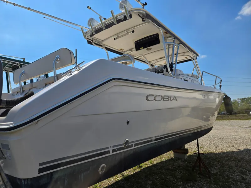 Slide: The Image of 2008 Cobia 316 Sport Cabin boat on land, side view under clear blue sky. - 6