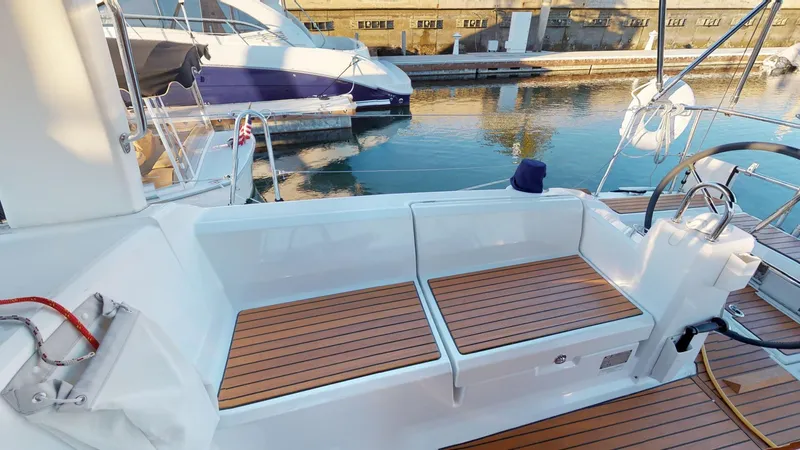 Slide: The Image of 2019 Beneteau Oceanis 38.1 yacht cockpit with wooden seating, docked by the water. - 11