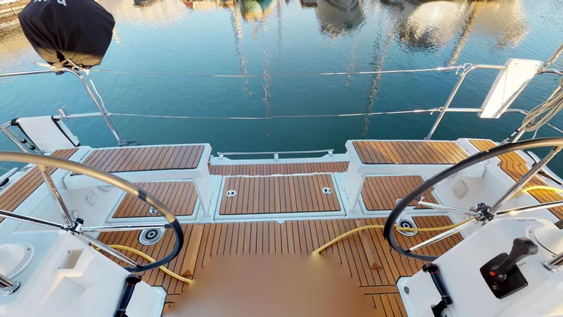 Slide: The Image of 2019 Beneteau Oceanis 38.1 yacht deck with dual steering wheels and teak flooring. - 14