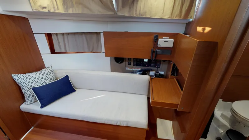 Slide: The Image of 2019 Beneteau Oceanis 38.1 interior with sofa, cushions, and navigation station. - 27