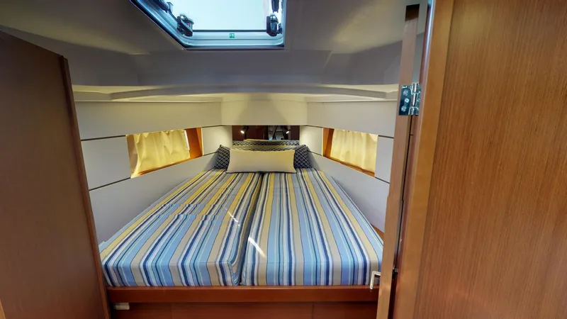 Slide: The Image of Cozy cabin interior of 2019 Beneteau Oceanis 38.1 with striped bedding and natural light. - 31