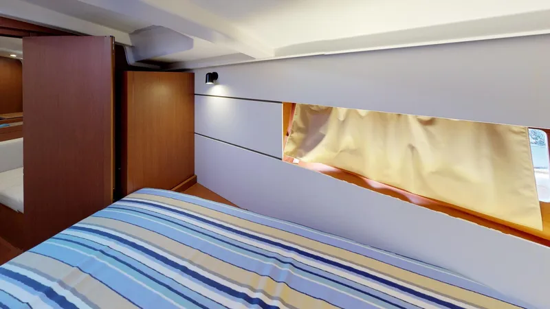 Slide: The Image of Interior cabin of 2019 Beneteau Oceanis 38.1 with striped bedding and window. - 35