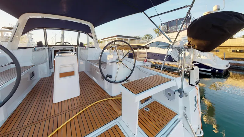 Slide: The Image of 2019 Beneteau Oceanis 38.1 yacht cockpit with dual steering wheels and teak flooring. - 38