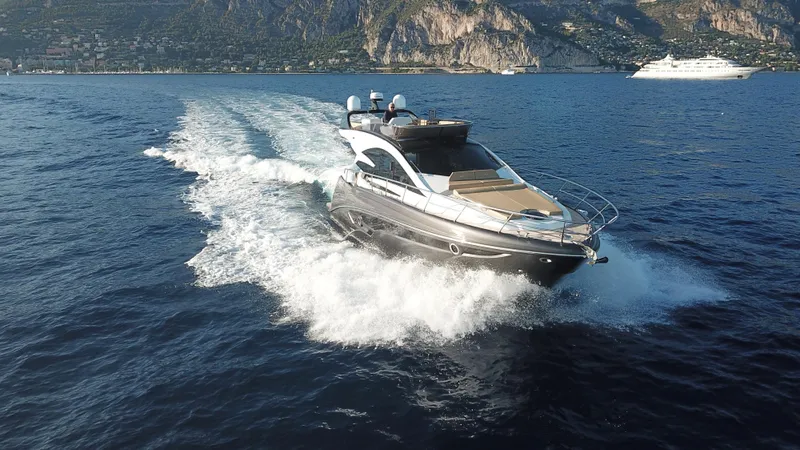 Slide: The Image of 2025 Cobrey 52 FLY yacht cruising on open water with scenic mountain backdrop. - 5