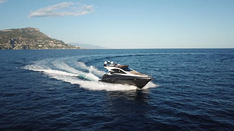 Slide: The Image of 2025 Cobrey 52 FLY yacht cruising on open sea with scenic coastal backdrop. - 7