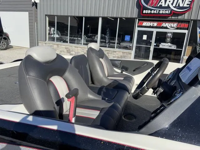 Slide: The Image of 2012 Ranger Z518 boat interior with gray and red seats, parked outside a marine shop. - 6