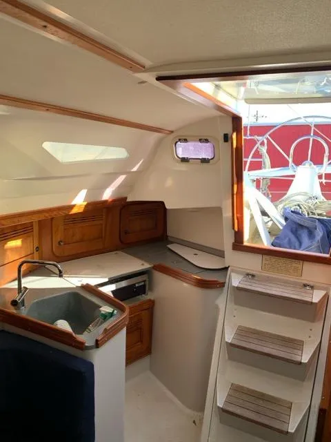 Slide: The Image of Interior of a 2002 C&C 99 sailboat, featuring a compact kitchen and wooden cabinetry. - 7