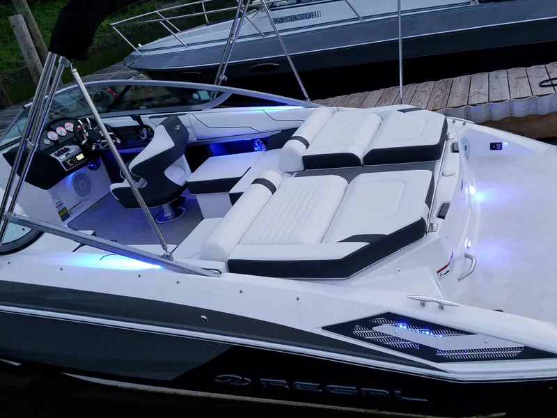 Slide: The Image of 2017 Regal 2100 boat with sleek design, illuminated seating, and modern dashboard at a dock. - 10