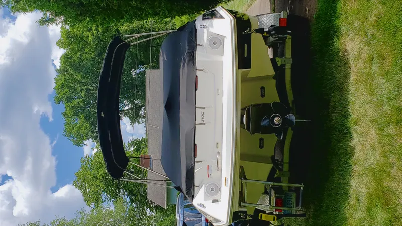 Slide: The Image of 2017 Regal 2100 boat with canopy, parked on grass under a blue sky. - 13