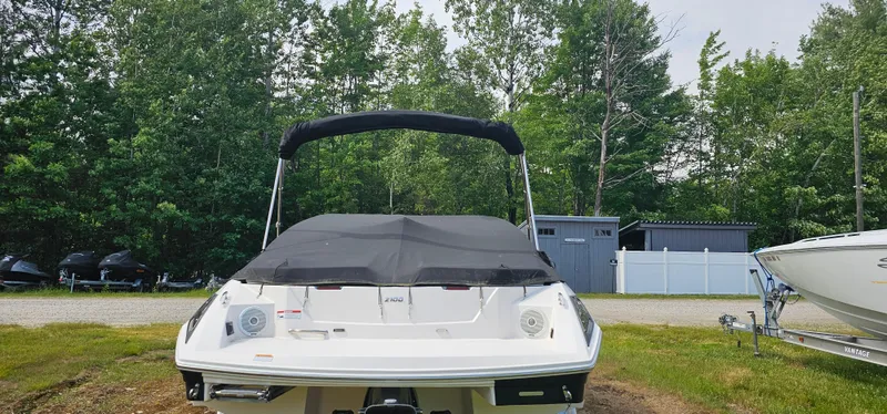 Slide: The Image of 2017 Regal 2100 boat with black cover, parked outdoors near trees and a shed. - 16