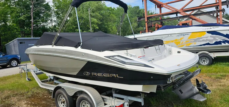 Slide: The Image of 2017 Regal 2100 boat on trailer, covered and parked outdoors. - 17