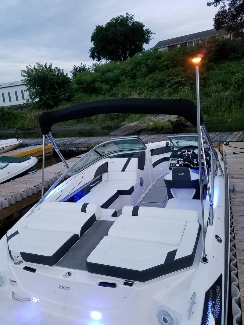 Slide: The Image of 2017 Regal 2100 boat docked, featuring sleek design and modern interior lighting. - 7