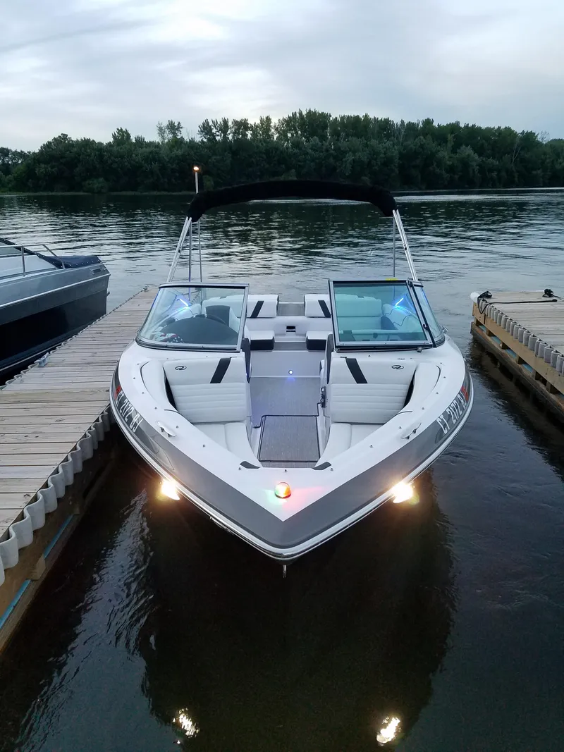 Slide: The Image of 2017 Regal 2100 boat docked on calm water, surrounded by trees. - 9