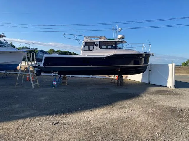 The Image of 2023 Ranger Tugs R25SC boat on dry land, blue hull, clear sky background. - 0
