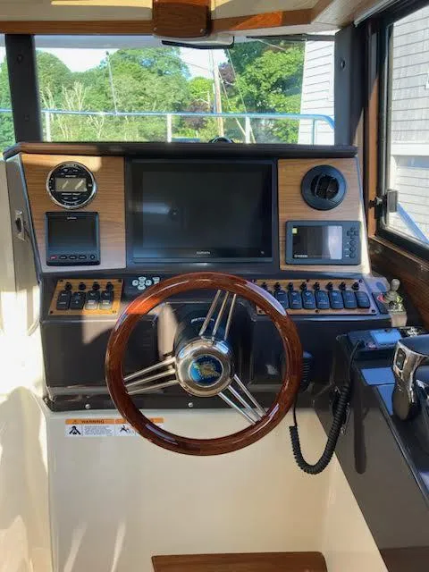 Slide: The Image of 2023 Ranger Tugs R25SC helm with wooden steering wheel and modern navigation equipment. - 10