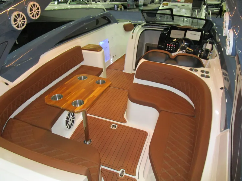 Slide: The Image of 2025 NX Boats N280 XTREME interior with brown seating and wooden table. - 8