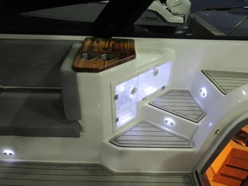 Slide: The Image of 2025 NX Boats 340 Sport Coupe interior with illuminated steps and wooden cup holder. - 14