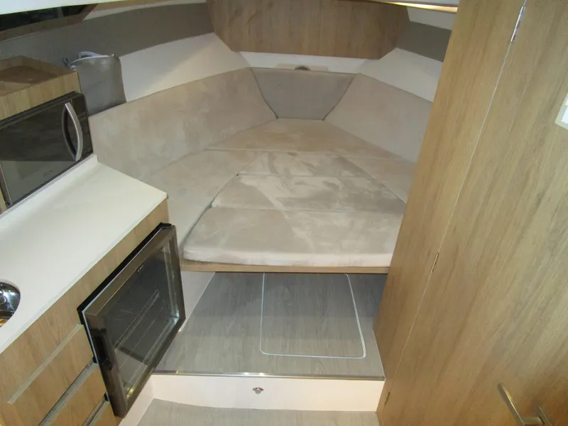 Slide: The Image of 2025 NX Boats 340 Sport Coupe interior with cozy bed and modern kitchenette. - 21
