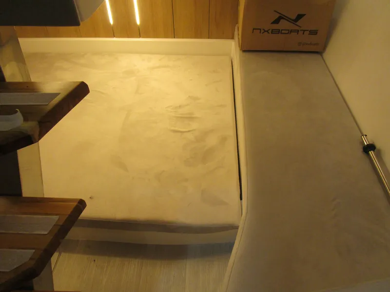 Slide: The Image of Interior of 2025 NX Boats 340 Sport Coupe, featuring a cozy seating area. - 24