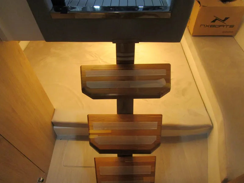 Slide: The Image of Interior stairs of 2025 NX Boats 340 Sport Coupe, featuring wooden steps and modern design. - 26