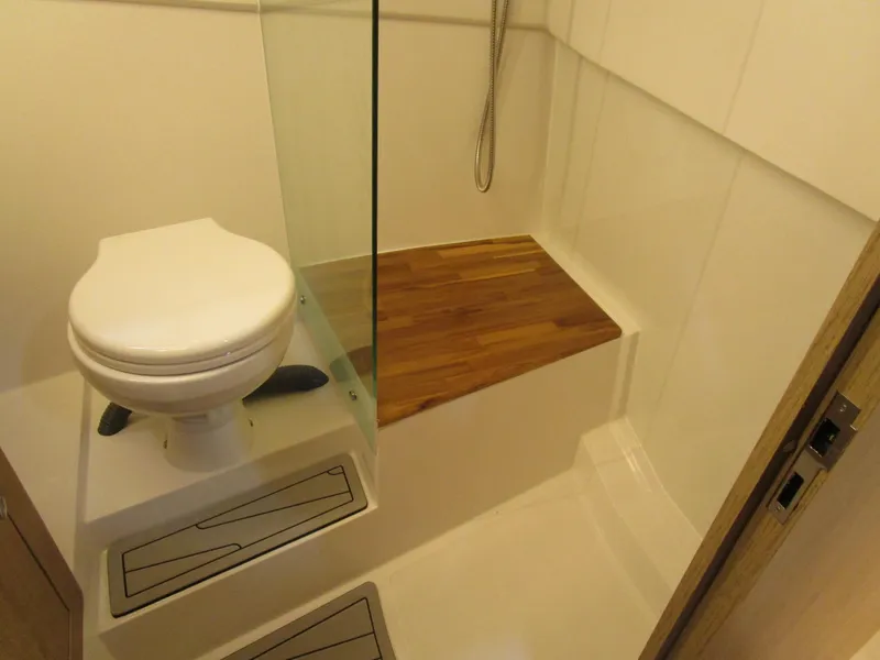 Slide: The Image of Bathroom interior of 2025 NX Boats 340 Sport Coupe with wooden shower seat. - 28