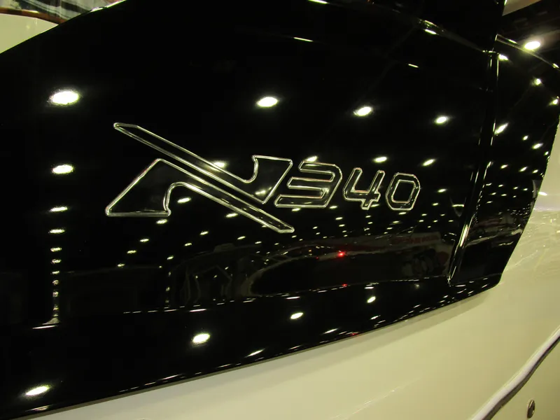 Slide: The Image of 2025 NX Boats 340 Sport Coupe logo on sleek black surface. - 35