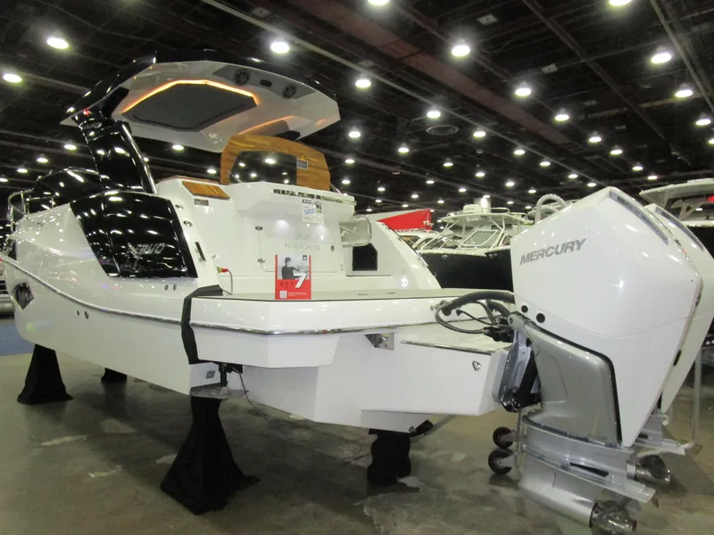 Slide: The Image of 2025 NX Boats 340 Sport Coupe displayed indoors with Mercury outboard engine. - 5