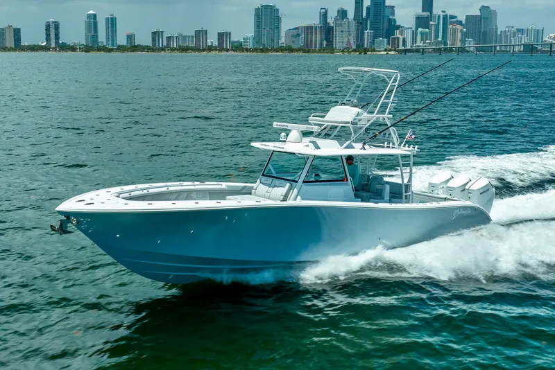 Slide: The Image of 2023 Yellowfin 42 Offshore boat cruising on water with city skyline in background. - 1