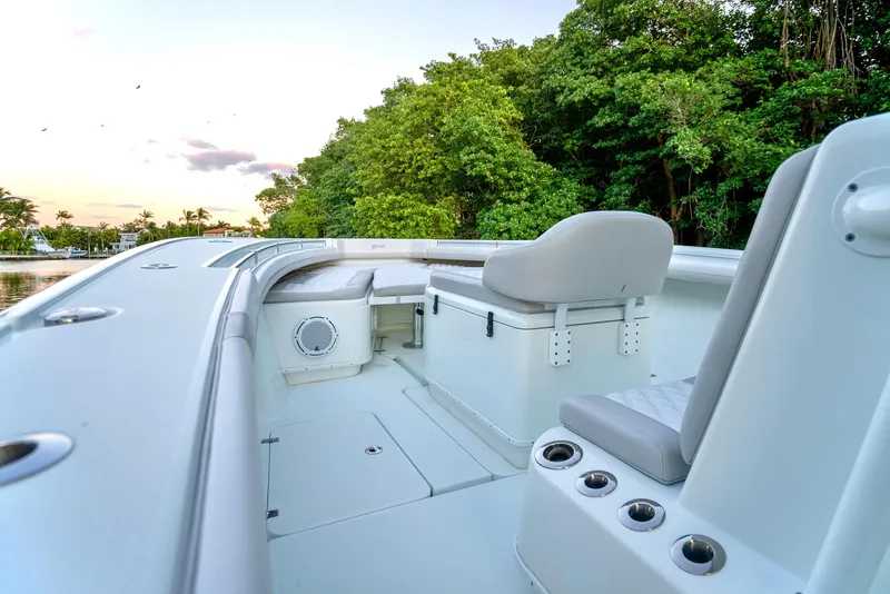Slide: The Image of 2016 Yellowfin 39 Offshore boat interior with seating and lush greenery in the background. - 23