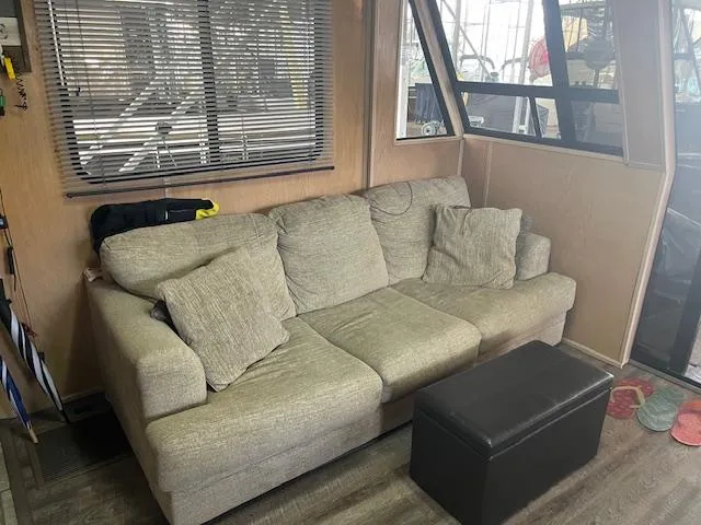 Slide: The Image of Cozy interior of 1988 Stardust Cruisers houseboat with a beige sofa and ottoman. - 4