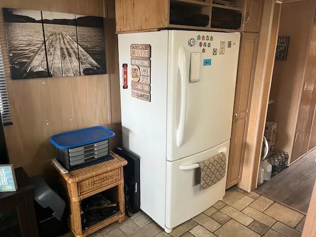 Slide: The Image of 1988 Stardust Cruisers houseboat interior with refrigerator, wicker table, and wall art. - 7