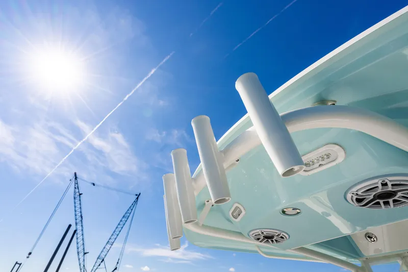 Slide: The Image of 2022 Cobia 240 CC boat under bright blue sky with sun and cranes. - 18