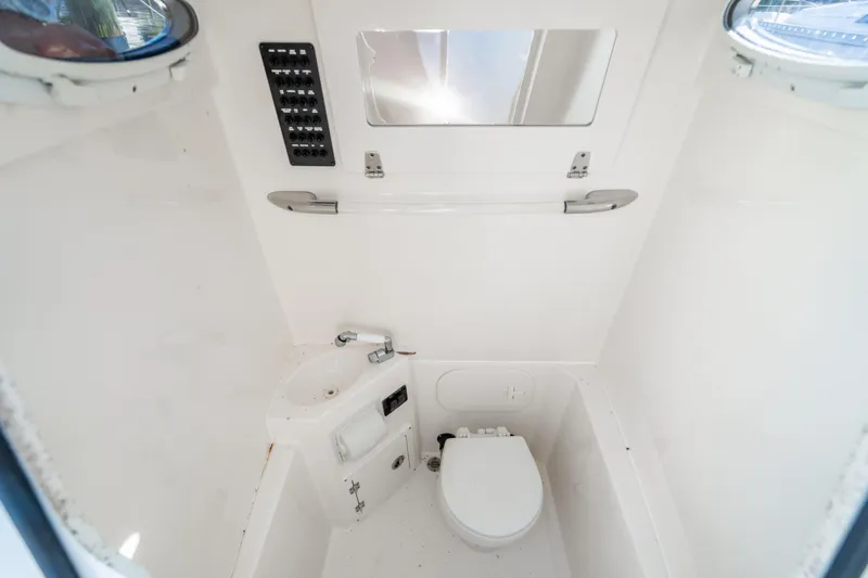 Slide: The Image of 2022 Cobia 240 CC boat interior with toilet, sink, and mirror. - 25