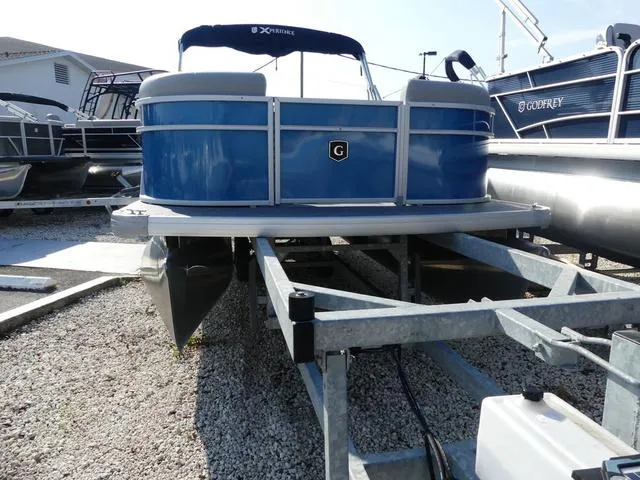 Slide: The Image of 2025 Godfrey Pontoons Xperience 1886 CX on trailer, blue exterior, parked outdoors. - 2