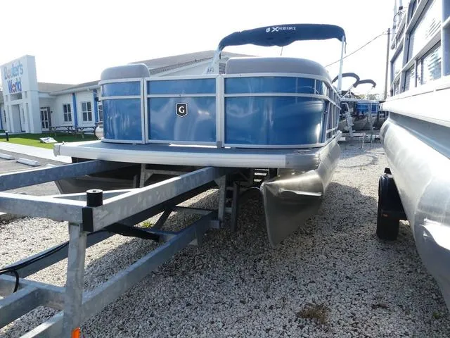 Slide: The Image of 2025 Godfrey Pontoons Xperience 1886 CX on trailer, blue exterior, parked on gravel. - 3