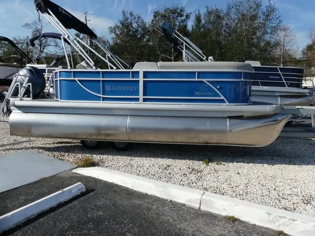 Slide: The Image of 2025 Godfrey Pontoons Xperience 1886 CX, blue pontoon boat, parked on gravel lot. - 4