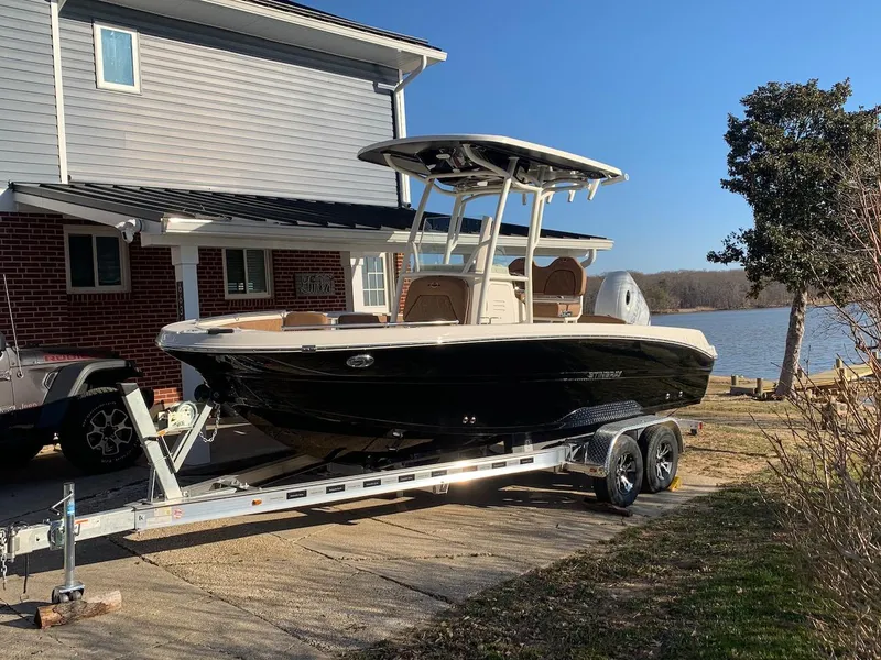 The Image of 2021 Stingray 216 CC boat on trailer by lakeside house. - 0