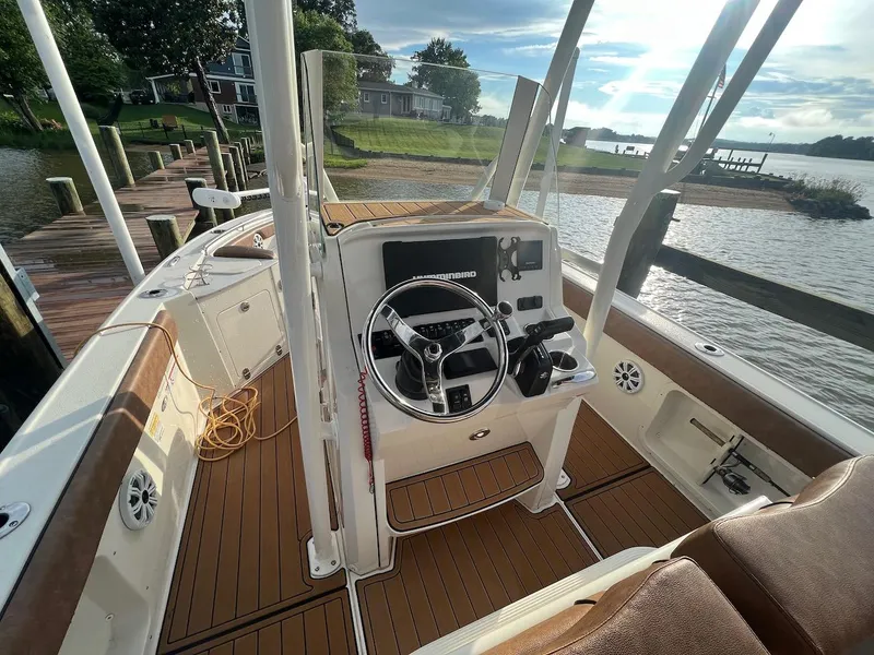 Slide: The Image of 2021 Stingray 216 CC boat interior with steering wheel, docked by a scenic waterfront. - 3