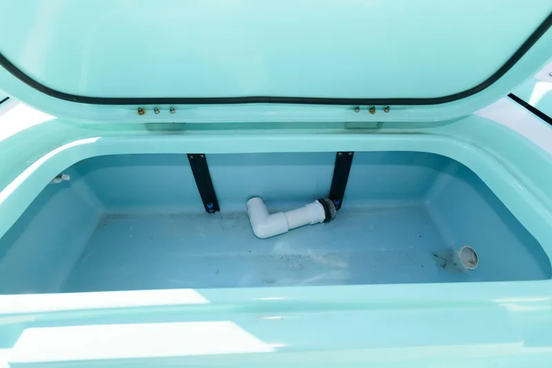 Slide: The Image of 2020 Shallow Sport 24 Modified V boat storage compartment with open lid and visible plumbing. - 19