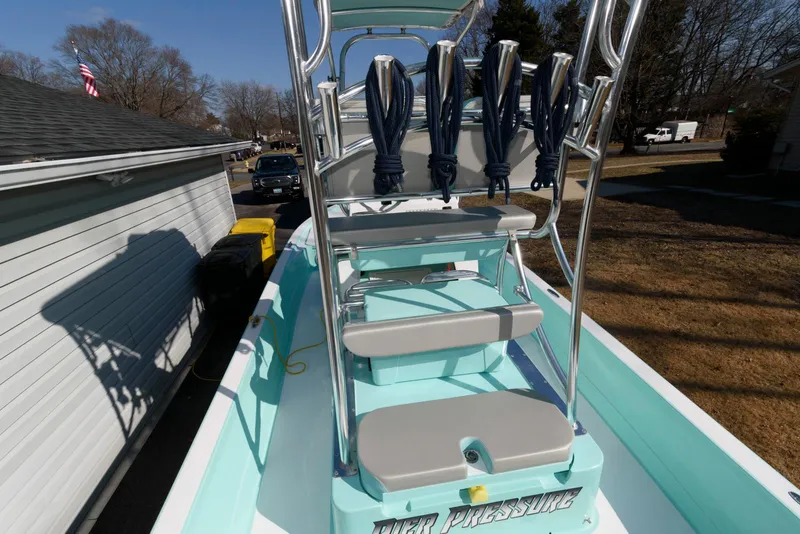 Slide: The Image of 2020 Shallow Sport 24 Modified V boat with rod holders and seating, parked outdoors. - 4