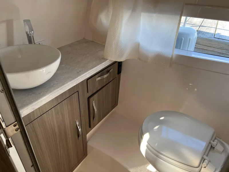 Slide: The Image of 2021 Regal 33 Express bathroom with modern sink, toilet, and wooden cabinetry. - 16