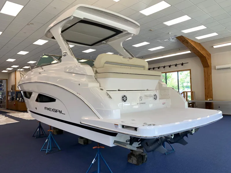 Slide: The Image of 2021 Regal 33 Express boat displayed indoors on stands, showcasing sleek design and spacious deck. - 23