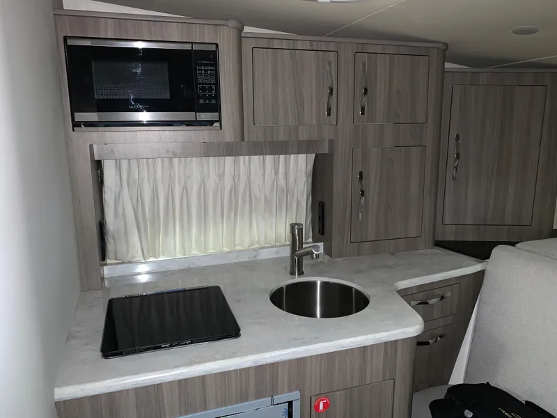 Slide: The Image of 2021 Regal 33 Express boat interior kitchen with microwave, sink, and cabinets. - 40